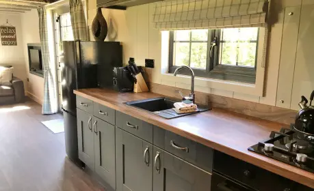 Walnut Lodge: A cosy tiny house for 4, with deck, hot tub, loungers, and a private lawn setting.