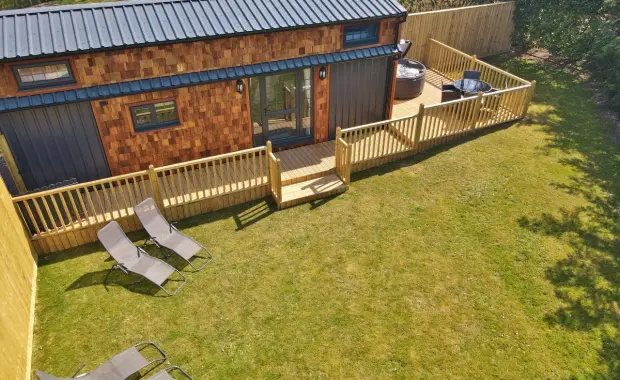 Walnut Lodge: A cosy tiny house for 4, with deck, hot tub, loungers, and a private lawn setting.
